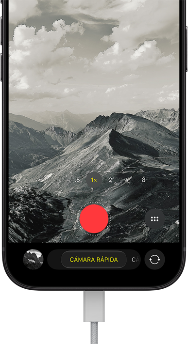 iPhone 18 Pro, parte frontal, se muestra un paisaje montañoso, con la interfaz de la app Cámara superpuesta en modo de cámara rápida, con el cable de corriente conectado al puerto de carga